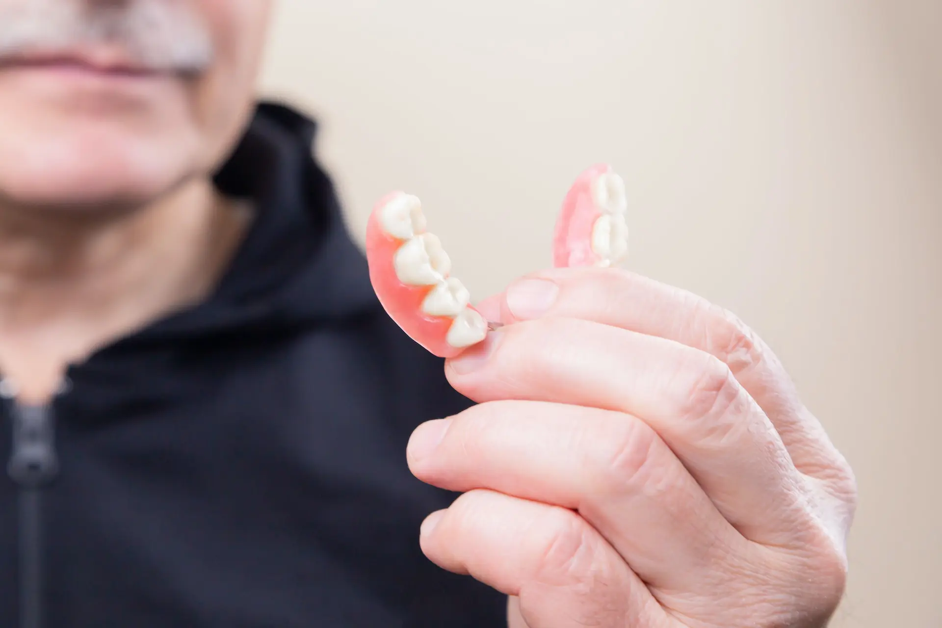 how to clean dentures - person holding bottom dentures