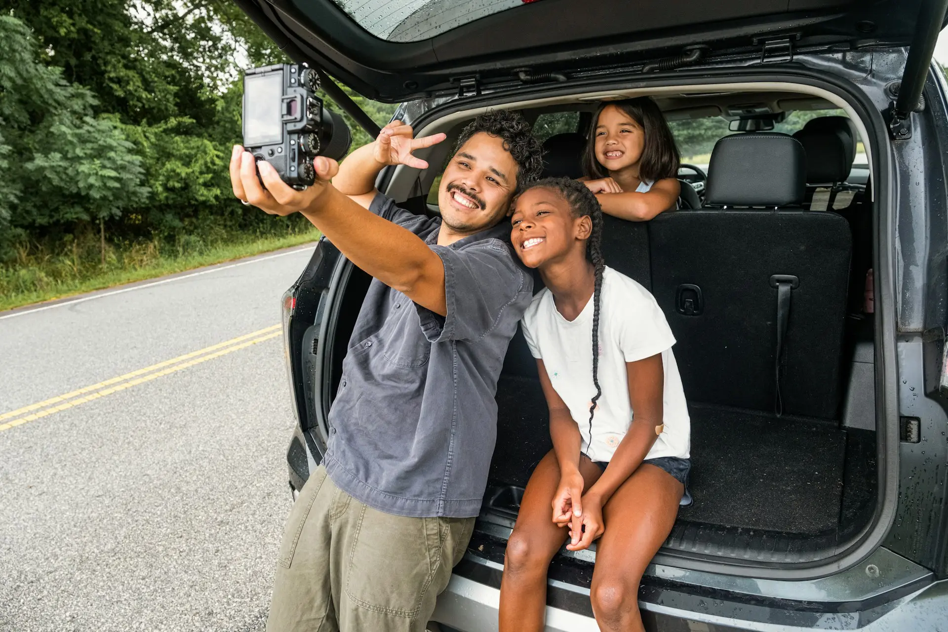 father and daughters traveling and smiling for the camera