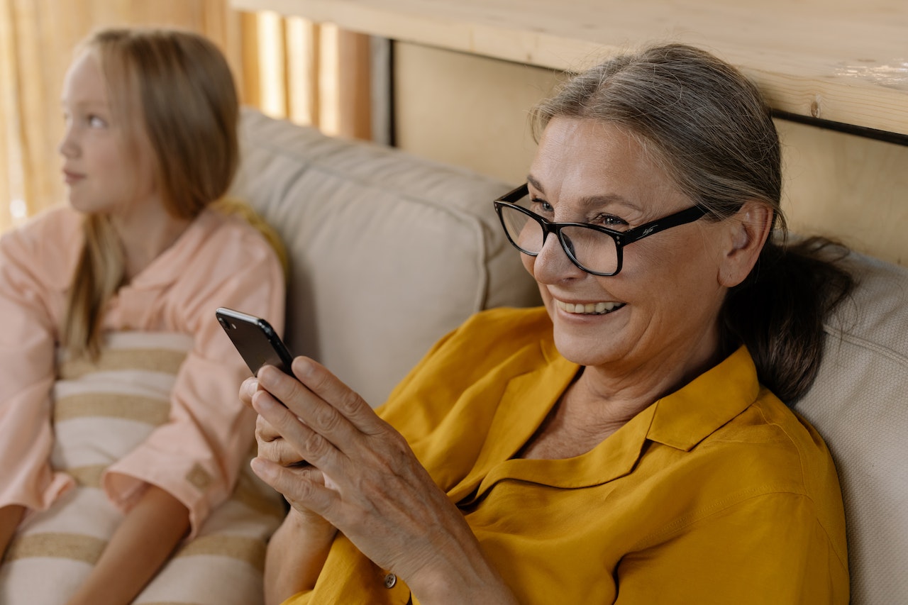 senior woman with glasses smiling looking at phone