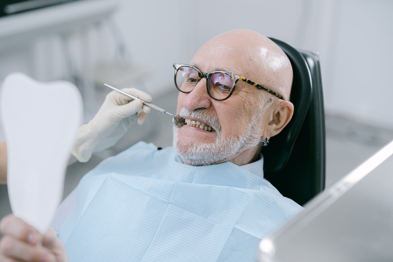 senior man in dentists chair looking in mirror