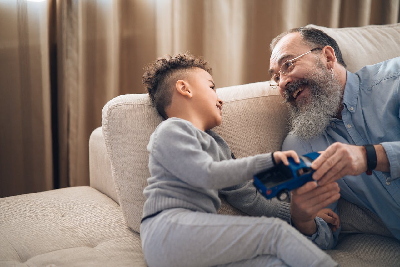 older man smiling and playing with grandson