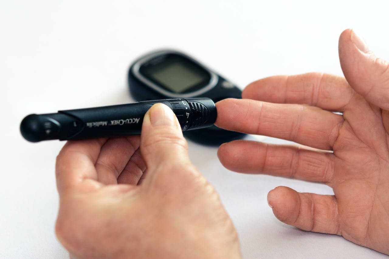 person using a black blood glucose meter on their finger