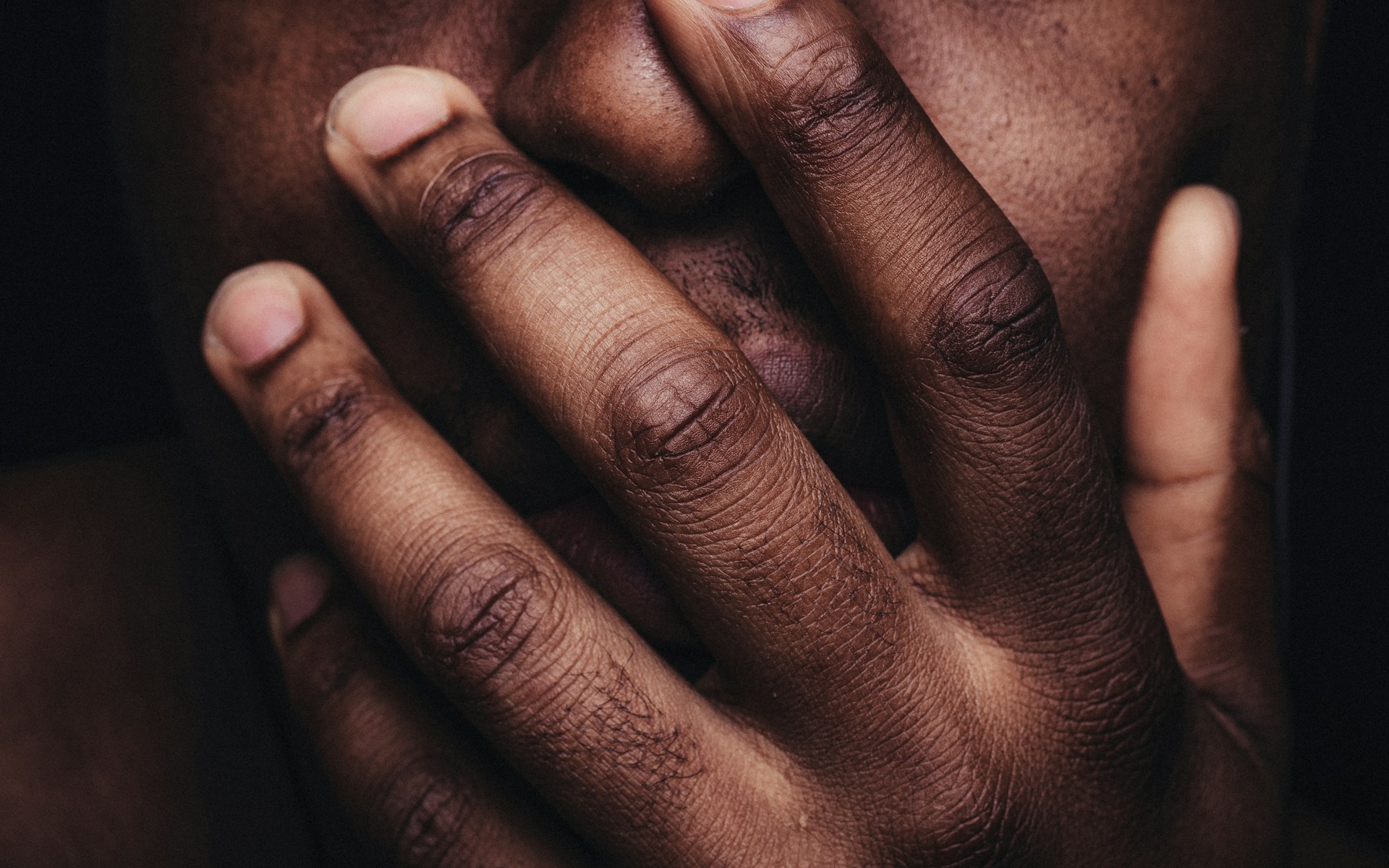 a closeup of a man's hand covering his face